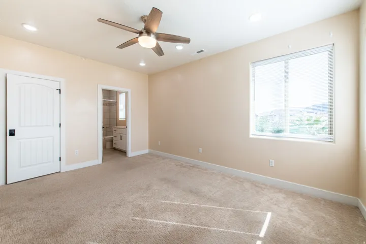 Unfurnished bedroom featuring connected bathroom, light carpet, ceiling fan, and recessed lighting