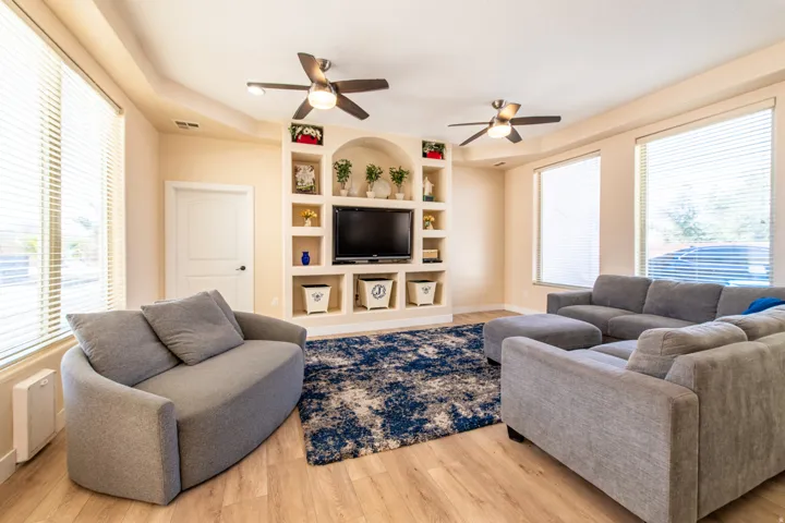 Living room with built in shelves, plenty of natural light, and light wood-type flooring