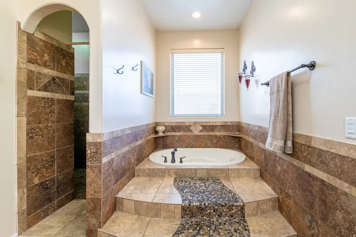 Full bath with a bath, tile walls, a wainscoted wall, and a walk in shower