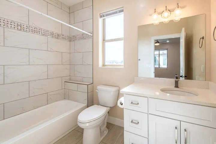 Full bath featuring vanity, washtub / shower combination, healthy amount of natural light, and a ceiling fan