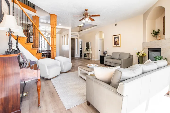 Living area with a textured ceiling, a high end fireplace, a ceiling fan, light wood-style flooring, and arched walkways