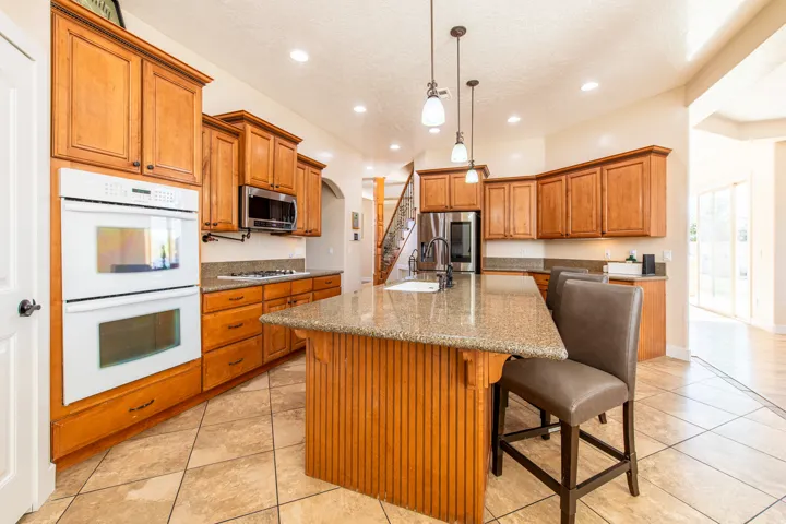 Kitchen with dark stone countertops, stainless steel appliances, wood finish cabinetry, a kitchen island with sink, and a breakfast bar