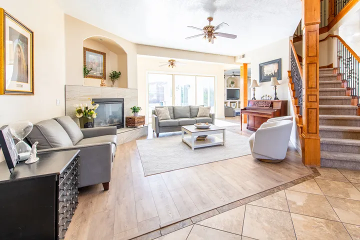 Living room with a tiled fireplace, a textured ceiling, light wood finished floors, and ceiling fan