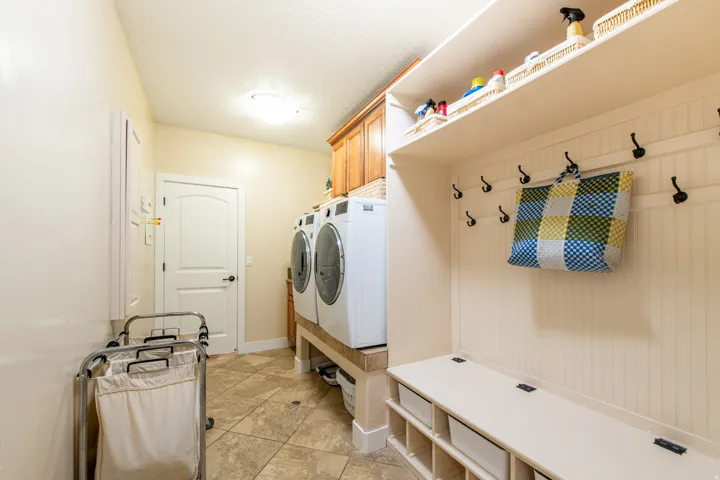 Laundry room featuring washing machine and dryer, cabinet space, and light tile patterned floors