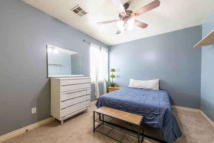 Bedroom with light carpet, a ceiling fan, and a textured ceiling