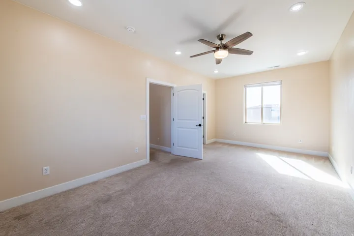 Empty room with light colored carpet, a ceiling fan, and recessed lighting