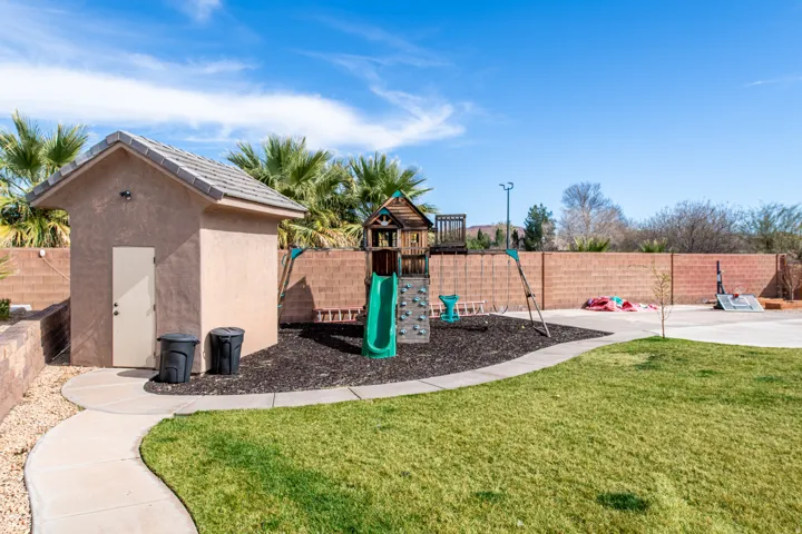 View of jungle gym featuring a fenced backyard and a storage shed