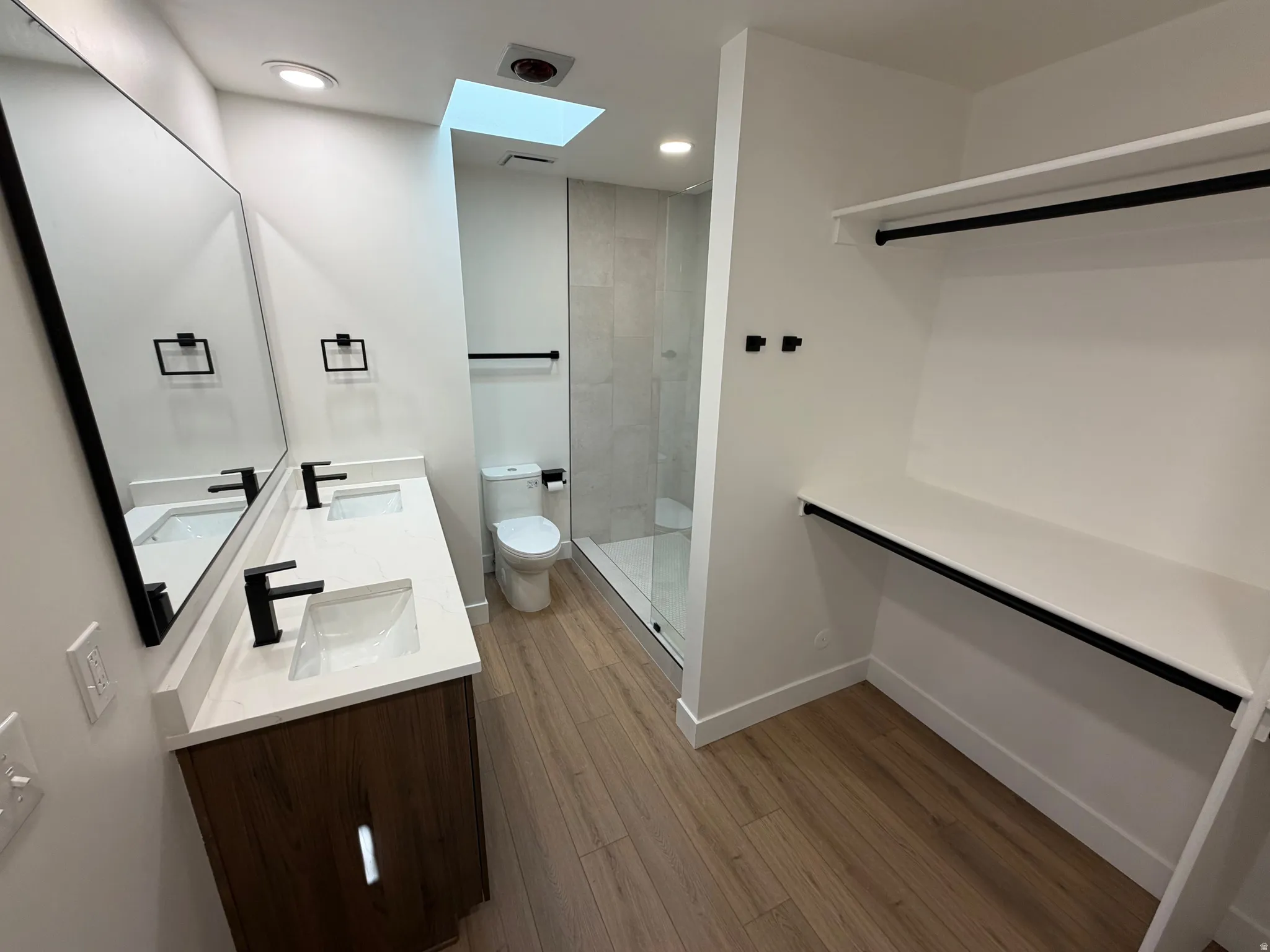 Bathroom with double vanity, dark wood-style floors, walk in shower, and recessed lighting