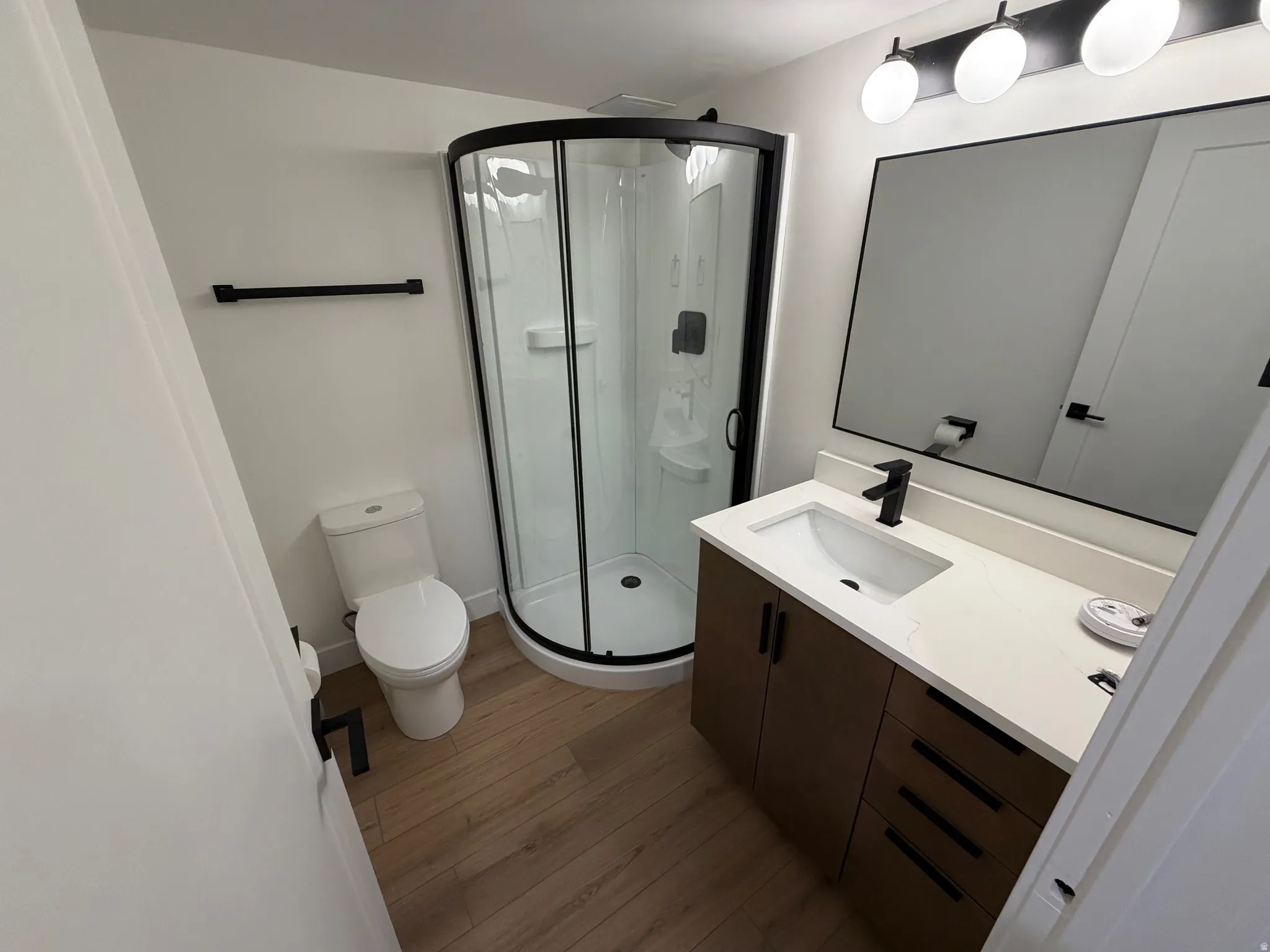 Bathroom with vanity, a shower stall, and dark wood-type flooring