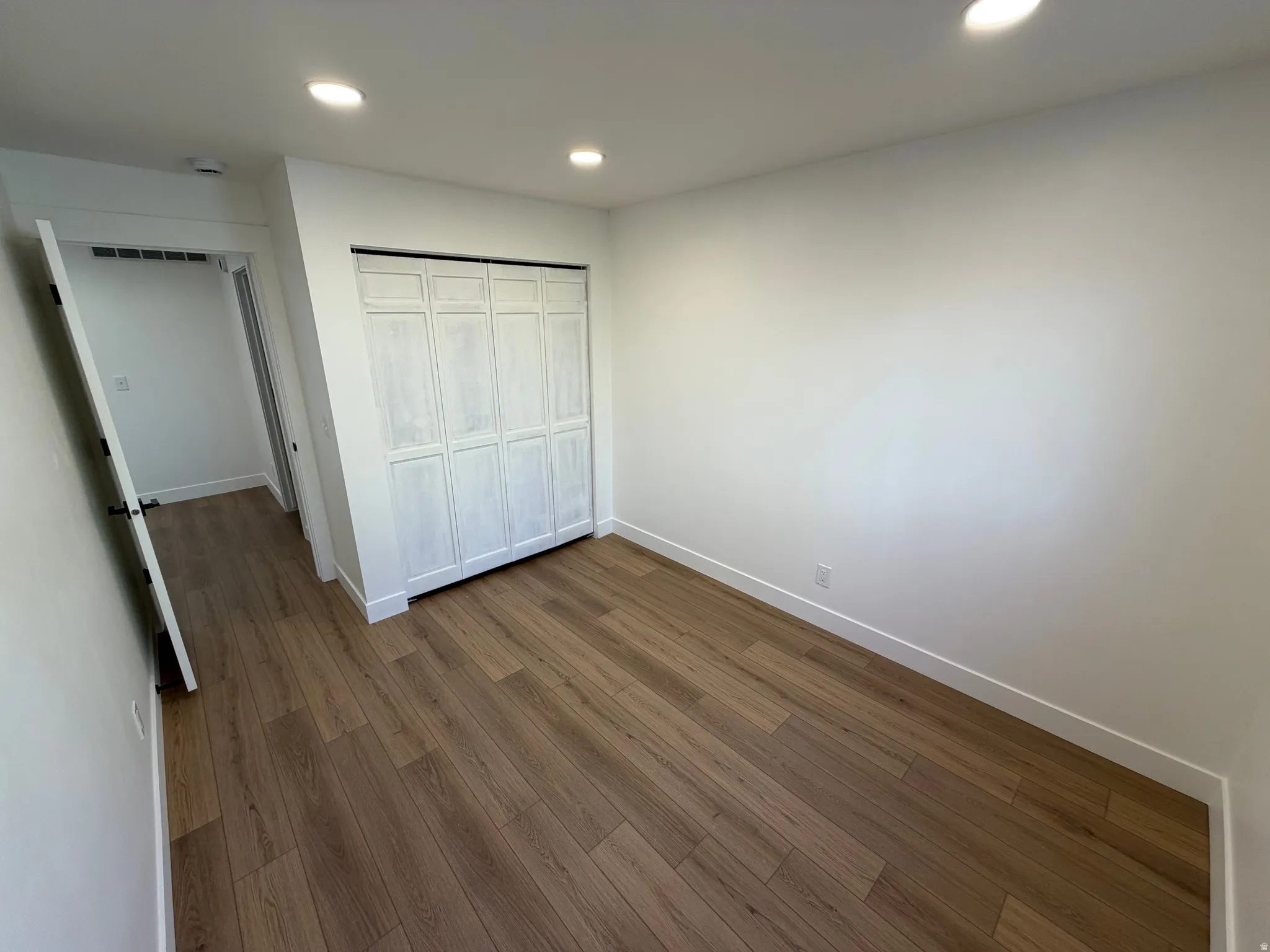 Unfurnished bedroom featuring dark wood finished floors, recessed lighting, and a closet