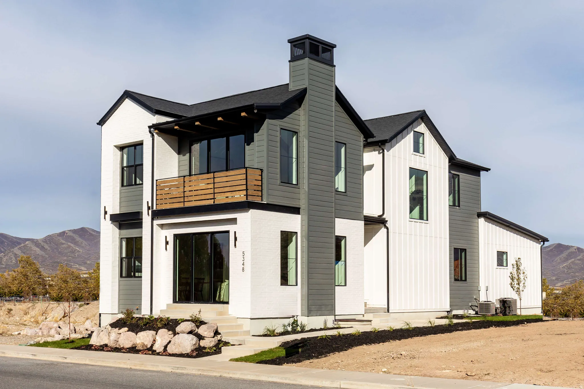 View of front of property with a mountain view, a balcony, a chimney, and board and batten siding