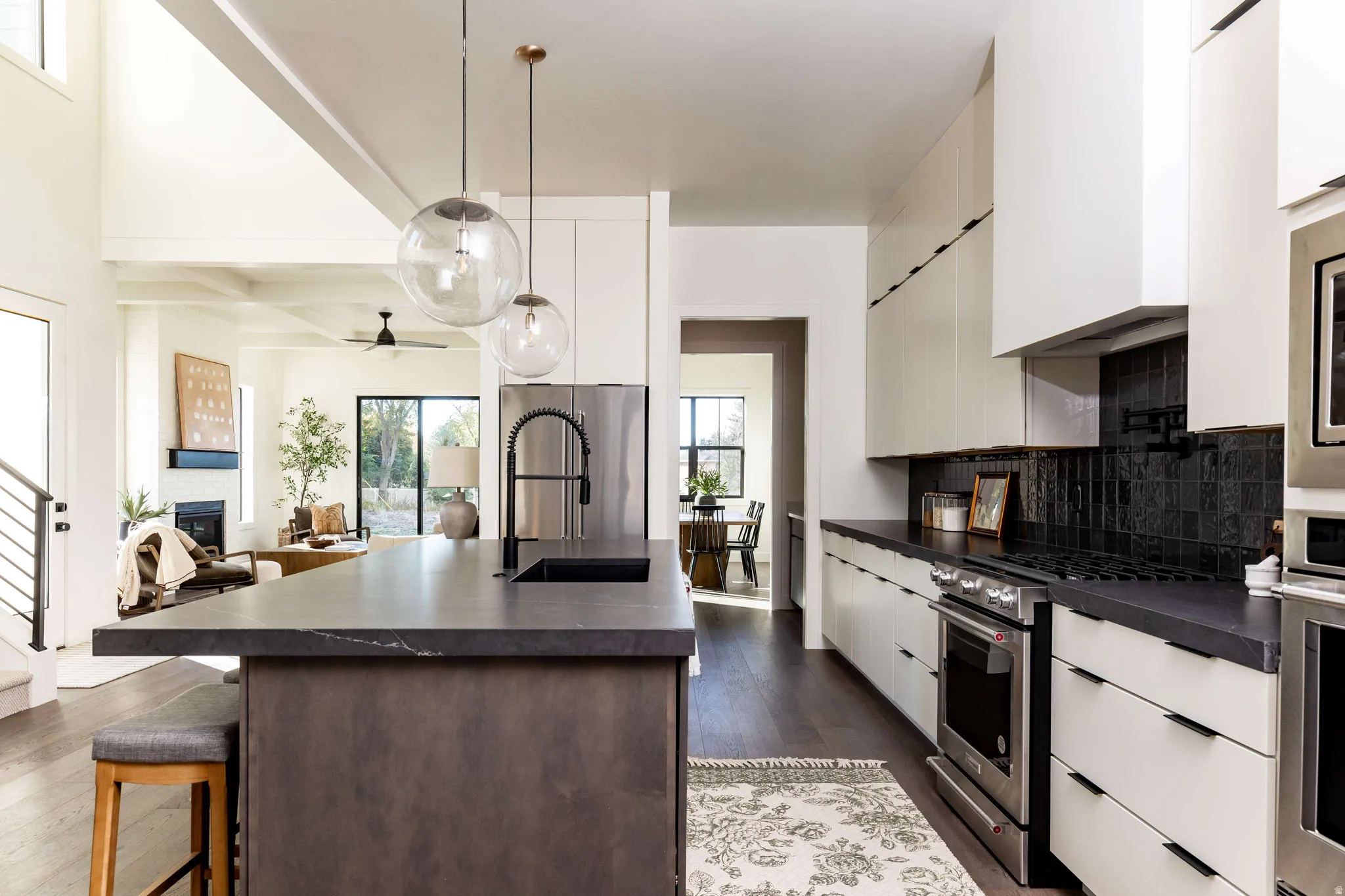 Kitchen featuring dark countertops, stainless steel appliances, white cabinetry, dark wood-style flooring, and beam ceiling