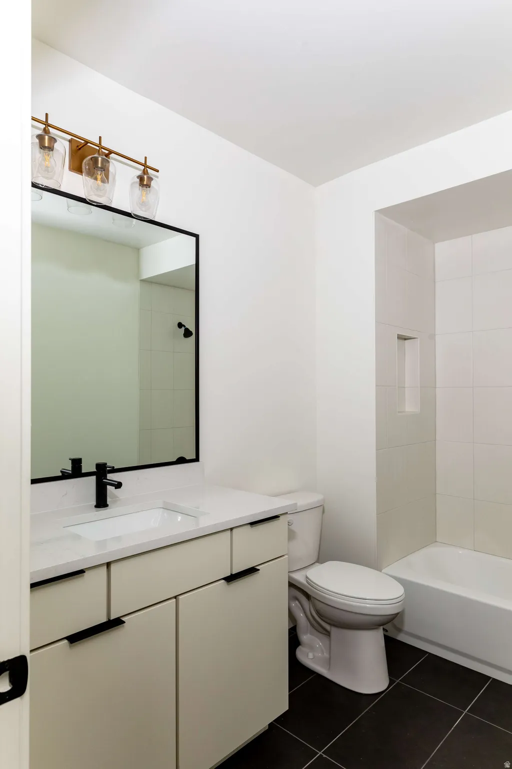 Full bath featuring vanity, dark tile patterned flooring, and tub / shower combination