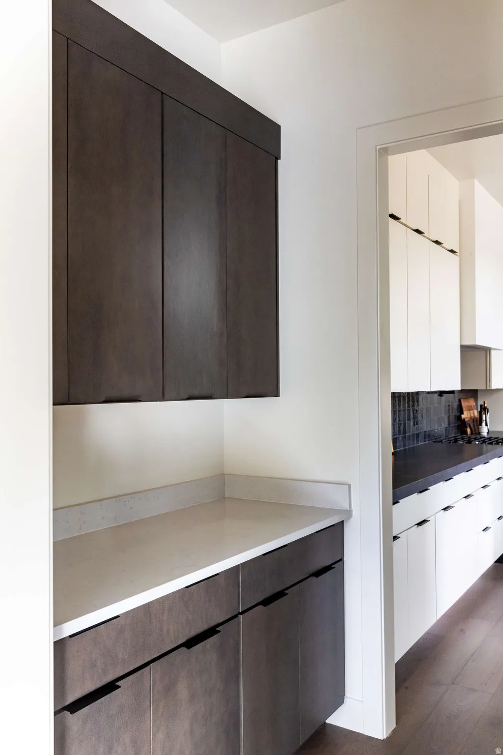 Kitchen featuring modern cabinets, dark wood-style flooring, tasteful backsplash, light countertops, and dark wood finish cabinets