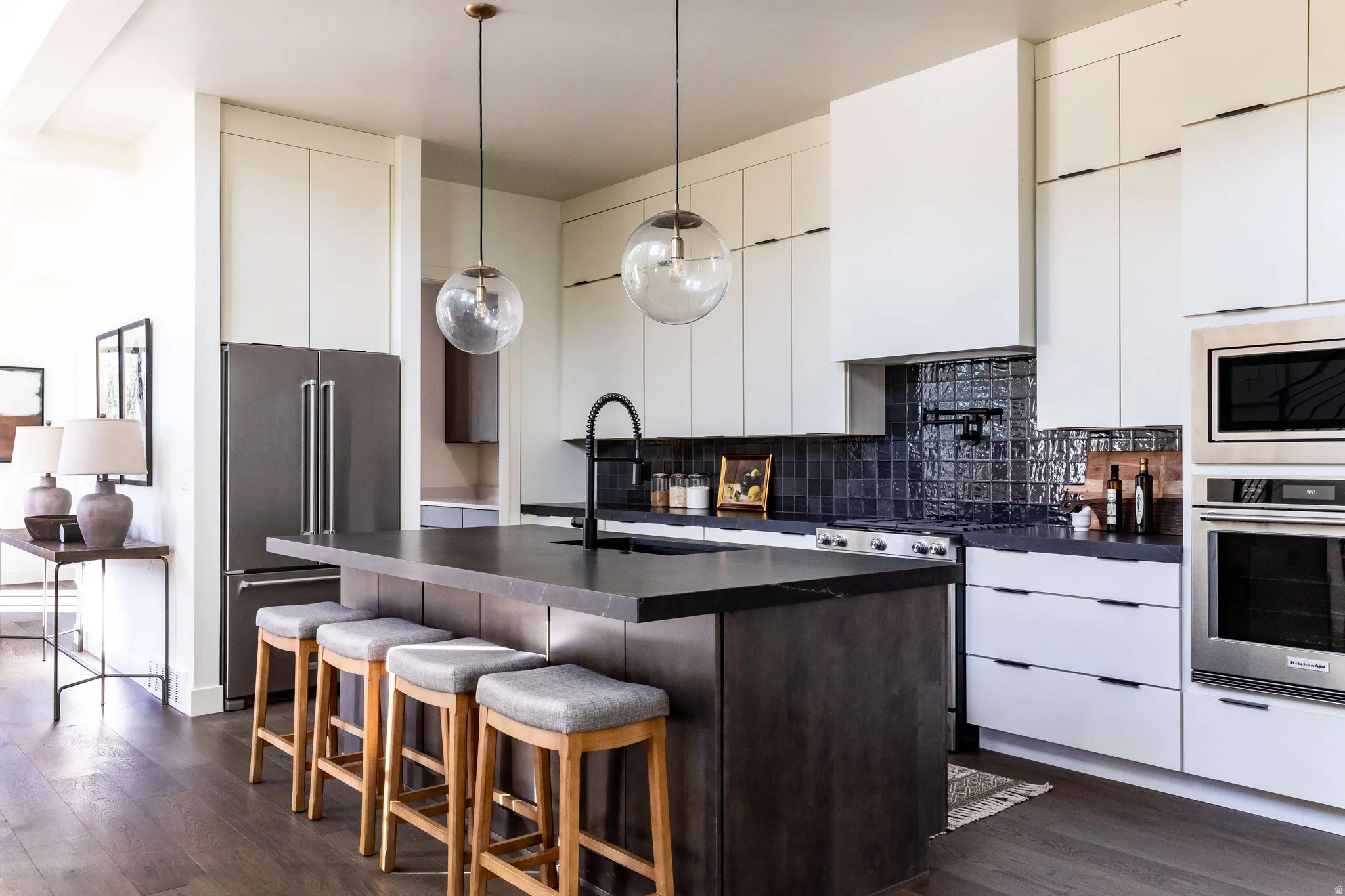 Kitchen with stainless steel appliances, dark wood-type flooring, a breakfast bar, hanging light fixtures, and two tone cabinets