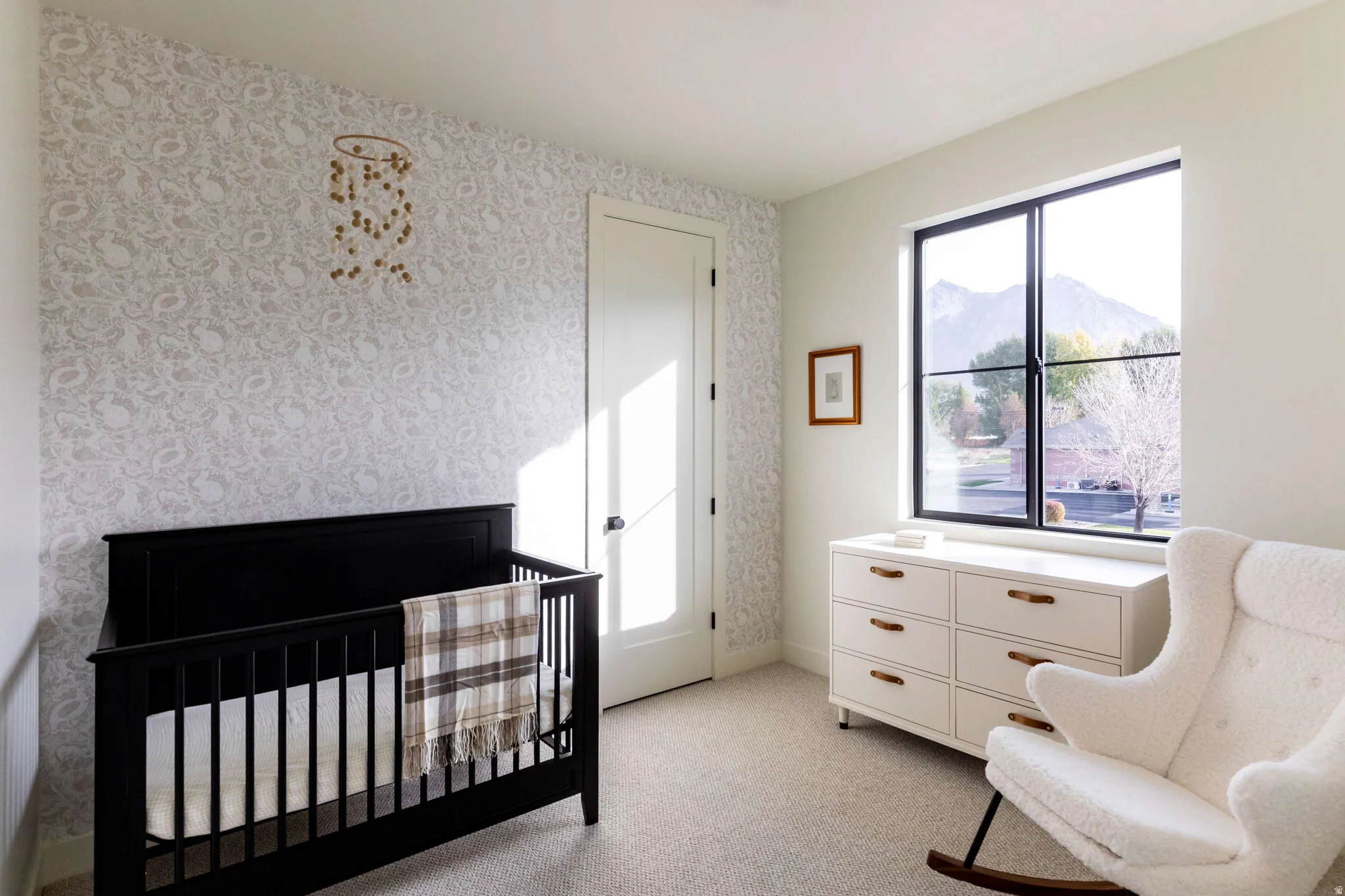 Bedroom featuring a nursery area, wallpapered walls, light colored carpet, and a mountain view