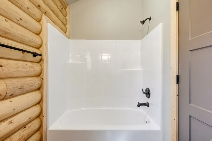 Full bath with shower / tub combination and log walls