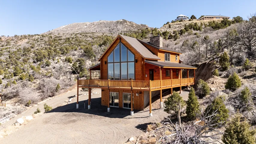 Rear view of property with log veneer siding, a chimney, dirt driveway, a metal roof, and a deck with mountain view