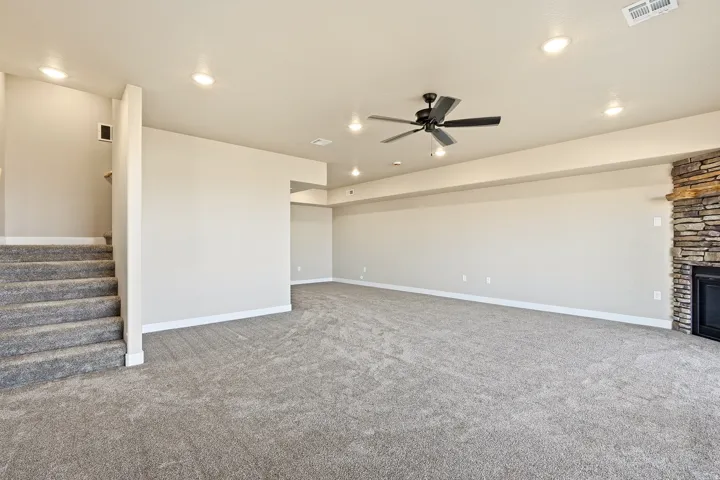 Unfurnished living room featuring carpet, a ceiling fan, a fireplace, and recessed lighting