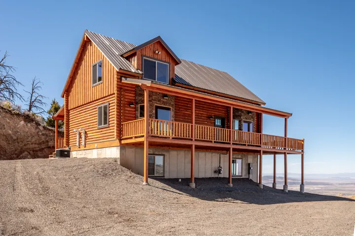 Rear view of property with covered porch, log exterior, a metal roof, and board and batten siding