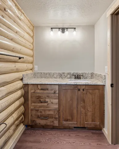 Bathroom with vanity, a textured ceiling, dark wood-type flooring, and log walls