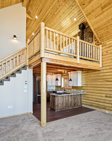 Kitchen featuring a peninsula, a high wooden ceiling, open floor plan, log walls, and dark colored carpet