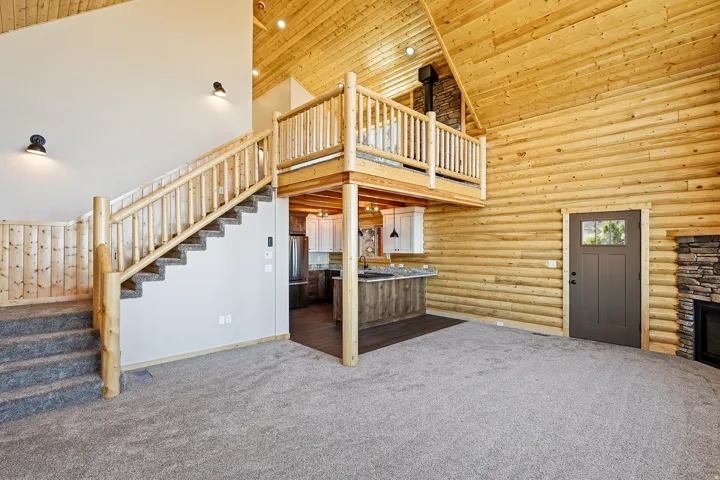 Unfurnished living room featuring dark colored carpet, rustic walls, a vaulted wood ceiling, a stone fireplace, and recessed lighting