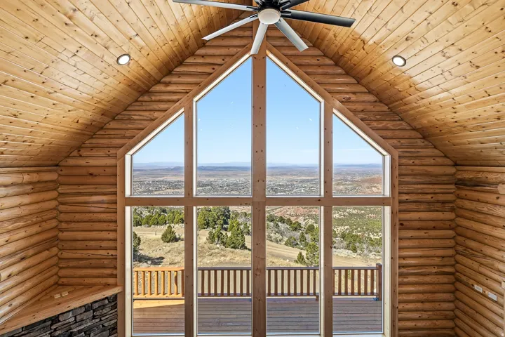 Unfurnished living room with log walls, a vaulted wood ceiling, and healthy amount of natural light