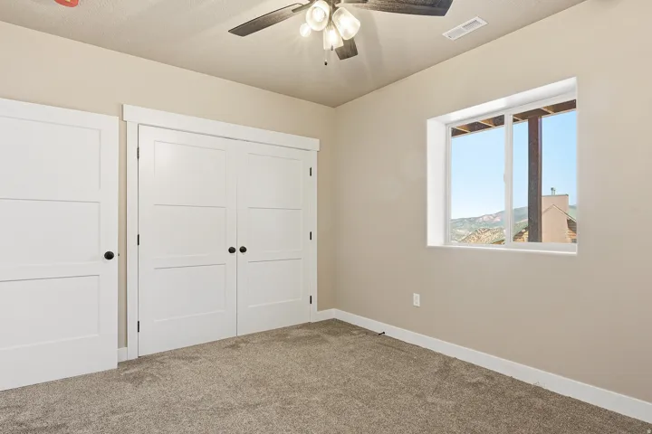 Unfurnished bedroom featuring a closet, carpet flooring, and a ceiling fan
