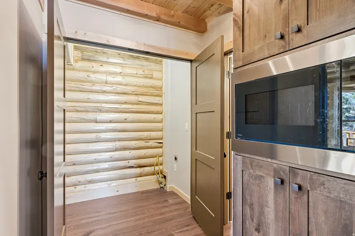 Kitchen featuring built in microwave, log walls, light wood-type flooring, and a wooden ceiling with exposed beams
