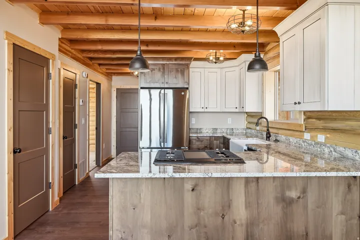 Kitchen with light stone counters, stainless steel appliances, a peninsula, dark wood-style floors, and pendant lighting