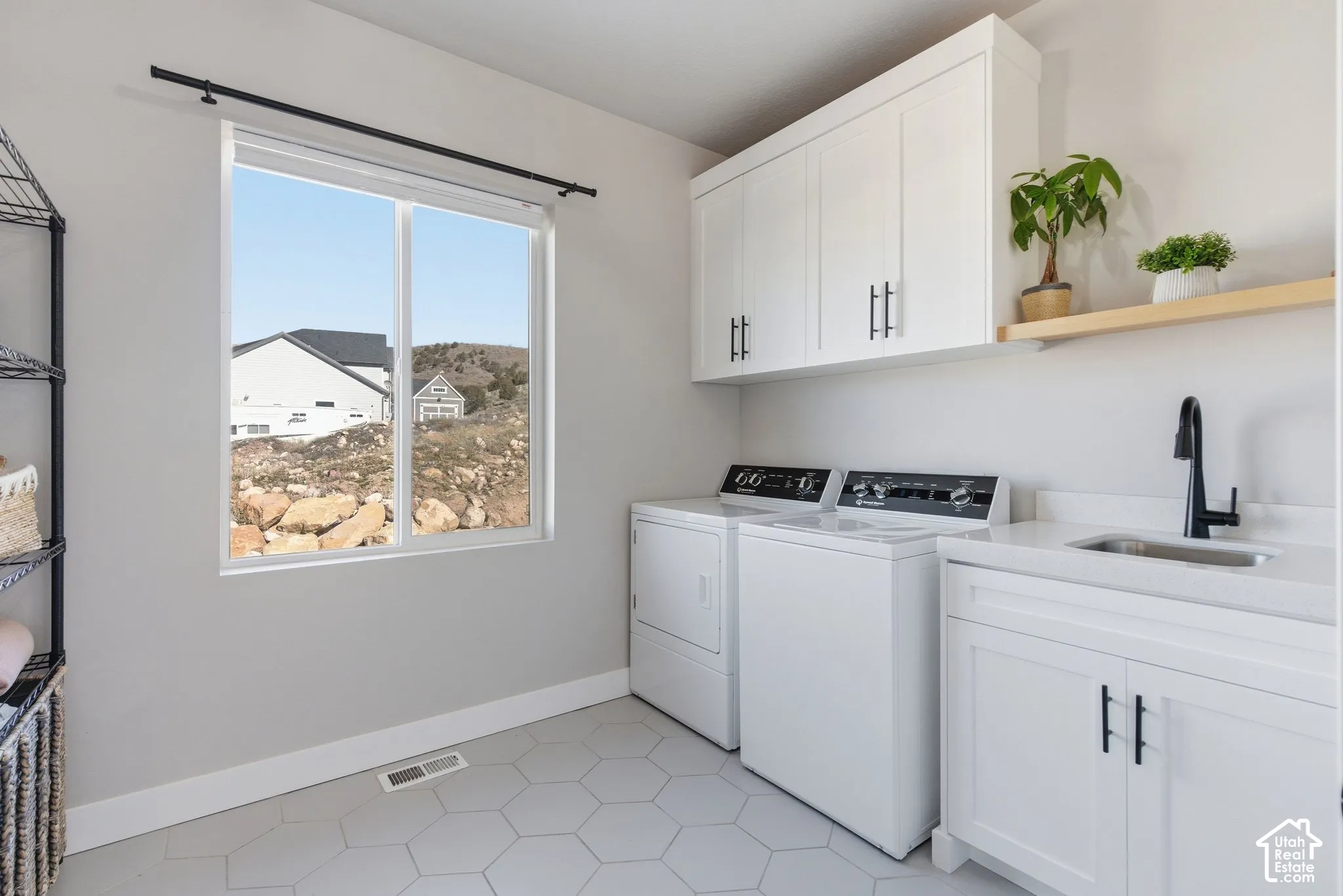 Laundry room featuring cabinet space,sink, light tile patterned floors, and independent washer and dryer; this property features two laundry areas. Both washers and dryers are included in the sale