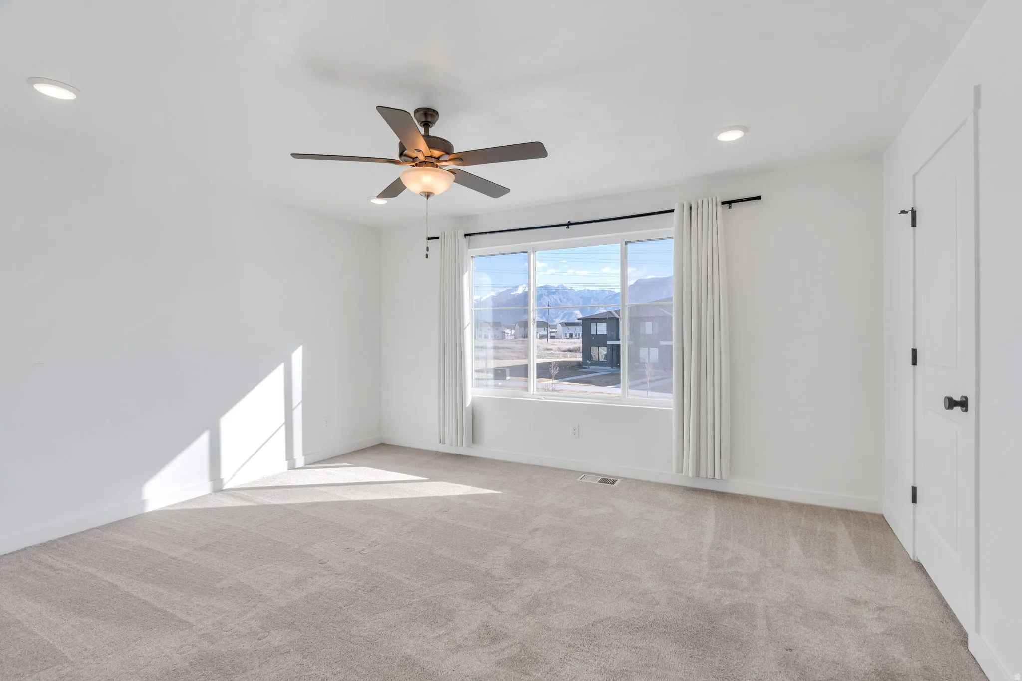 Empty room with light colored carpet, a mountain view, a ceiling fan, and recessed lighting