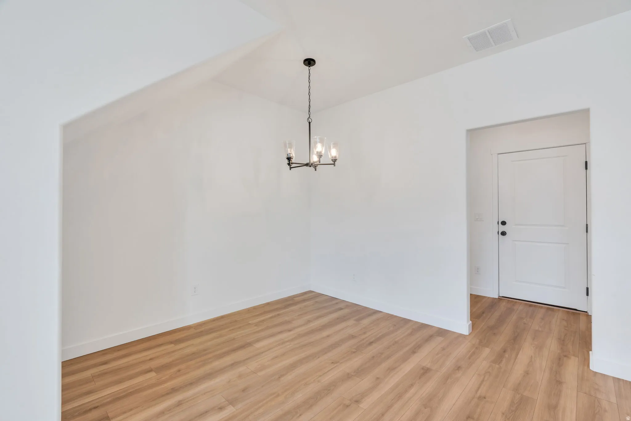 Unfurnished dining area featuring light wood-style flooring and a chandelier