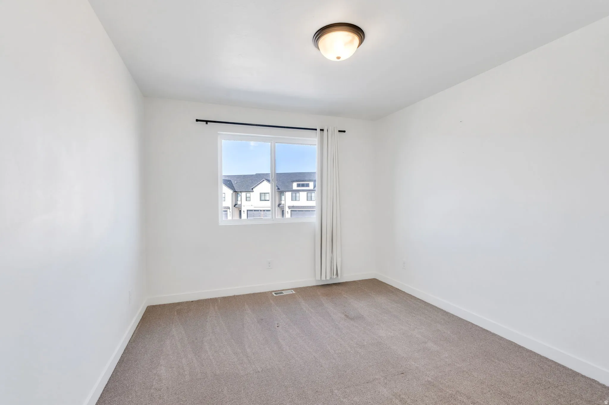 Spare room with light colored carpet and baseboards