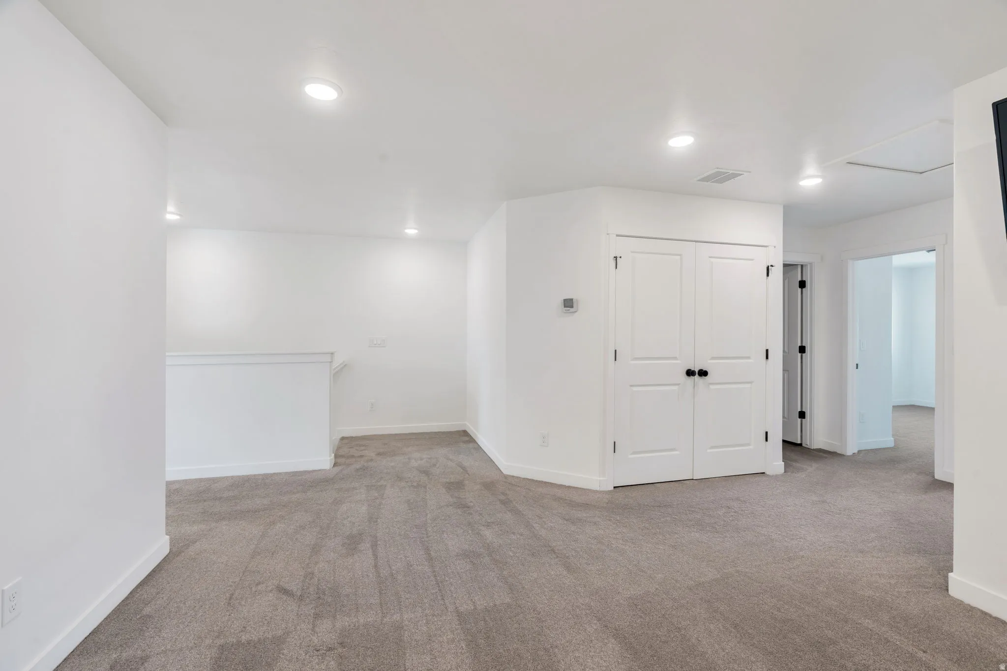 Empty room with light carpet and recessed lighting
