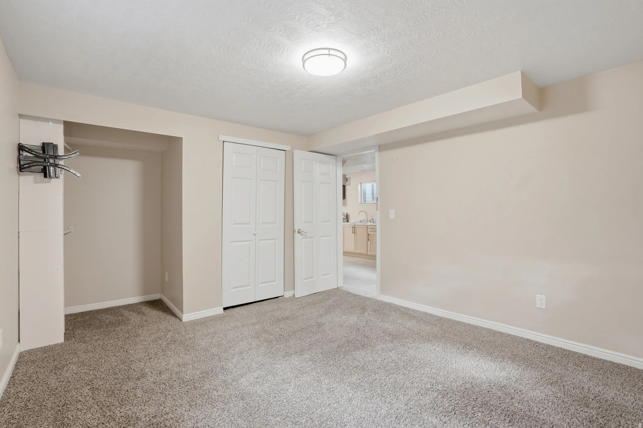 Unfurnished bedroom featuring light carpet, a textured ceiling, and a closet