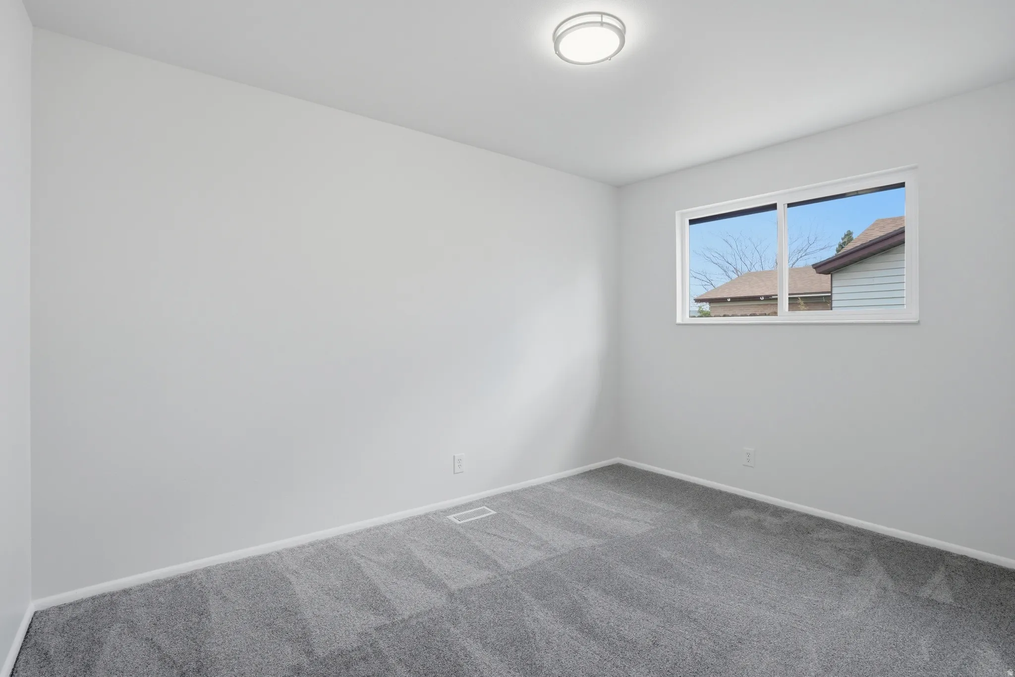 Carpeted spare room featuring baseboards