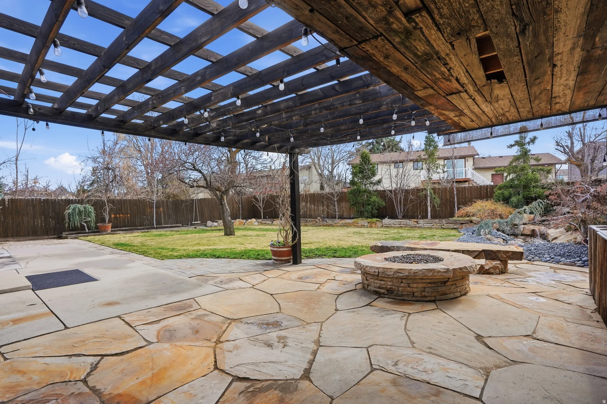 Fenced backyard with an outdoor fire pit, a pergola, and a patio area