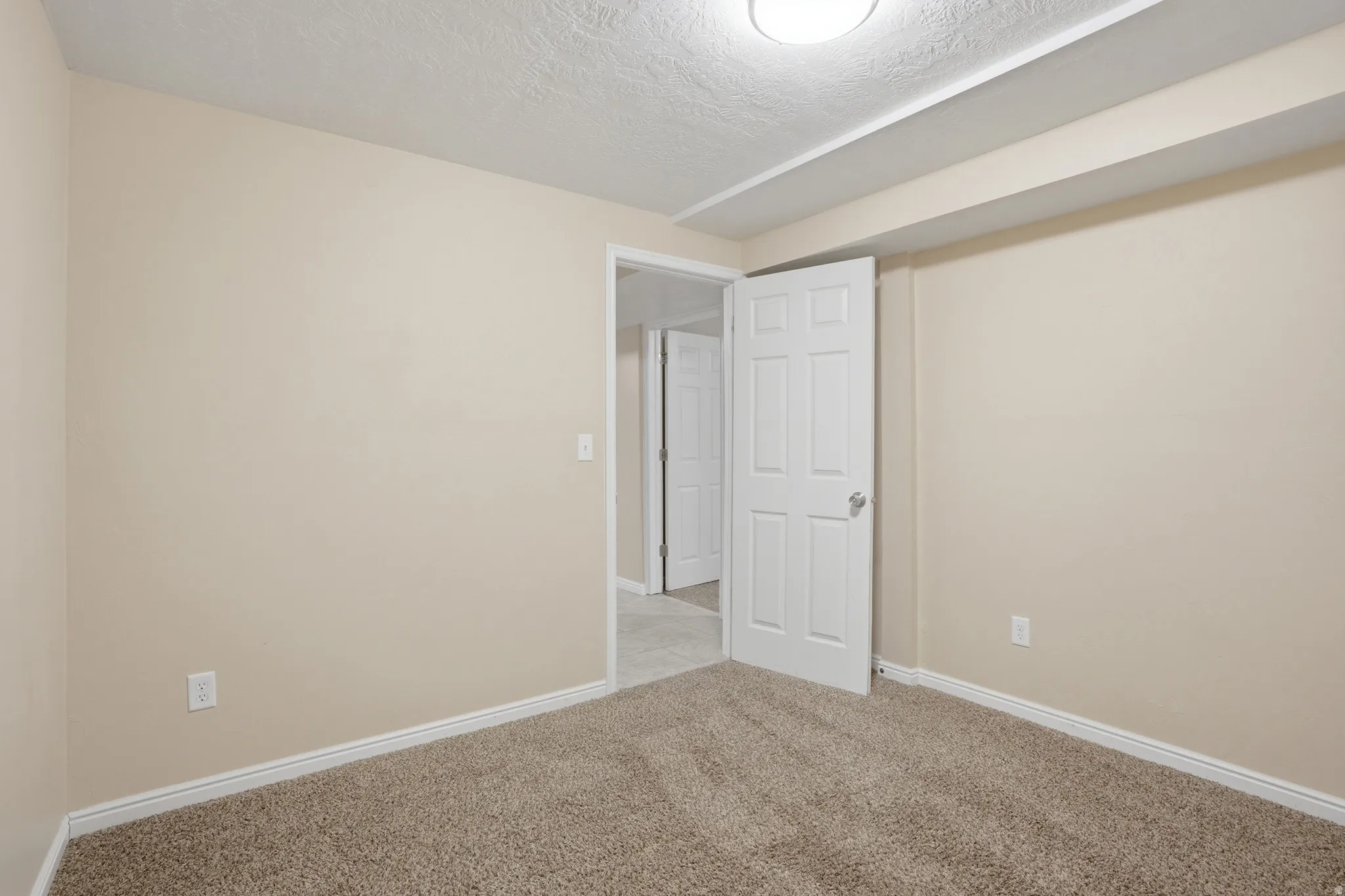 Spare room with a textured ceiling and light carpet