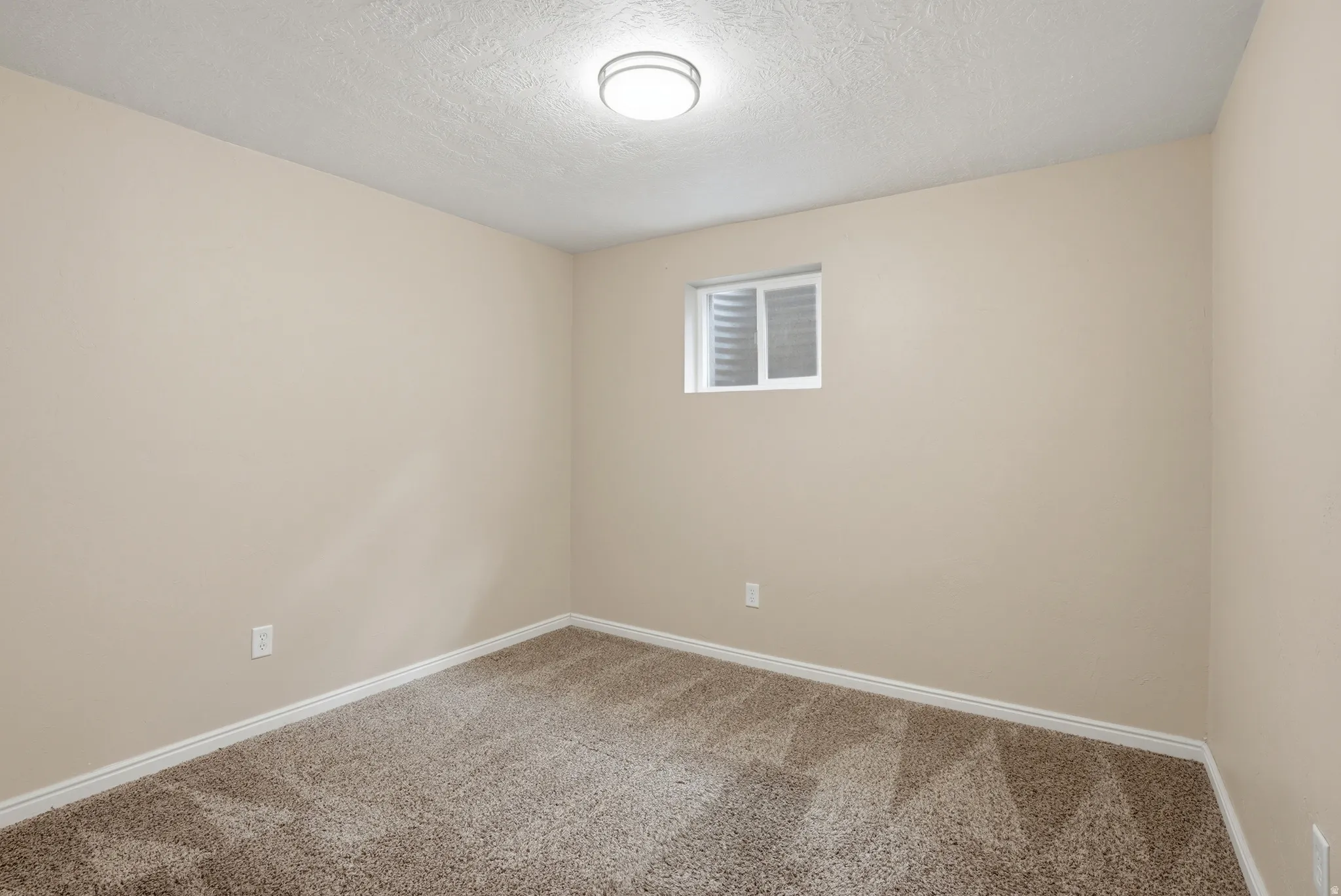 Carpeted spare room featuring a textured ceiling