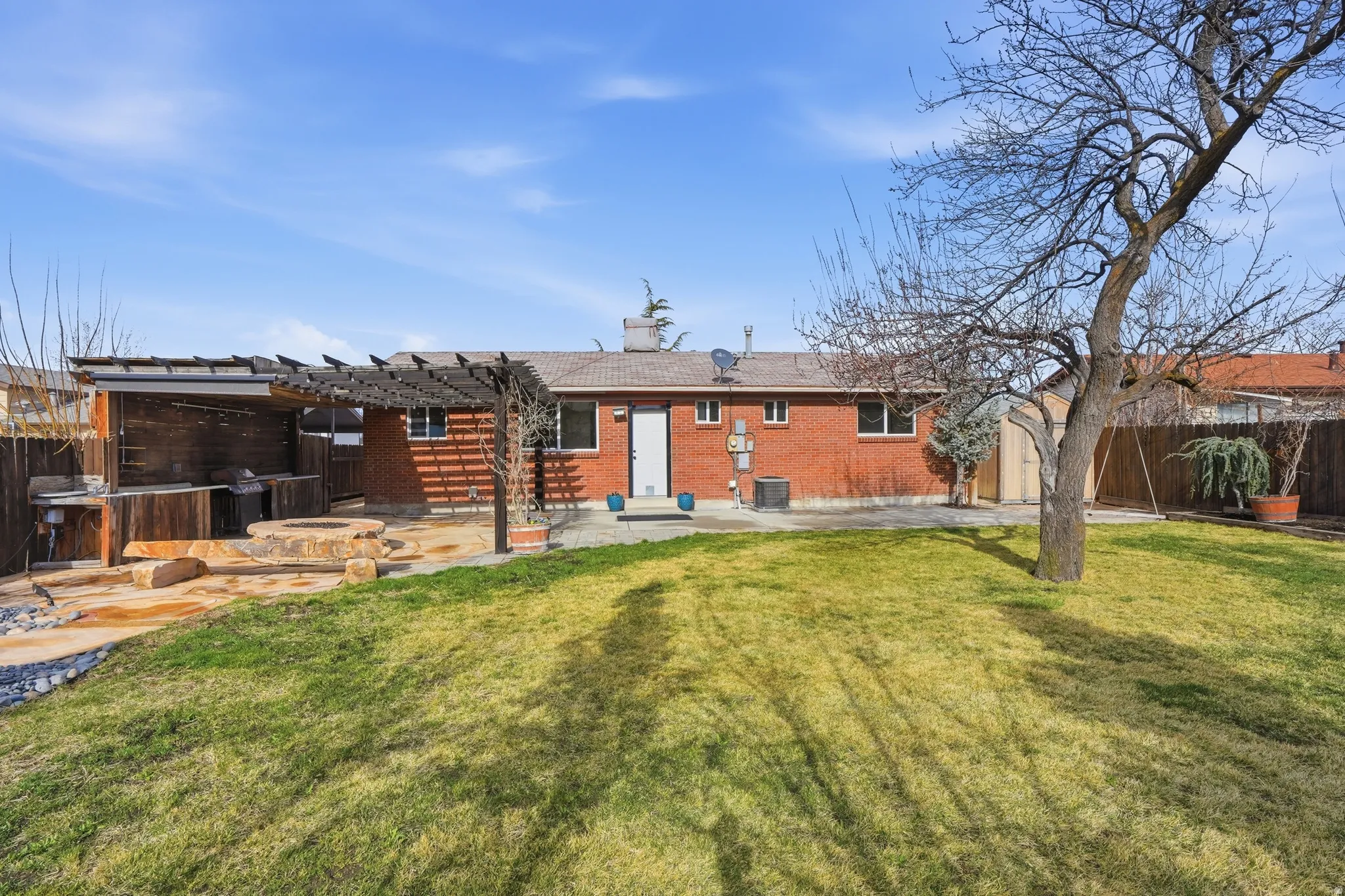 Rear view of house featuring a fenced backyard, brick siding, a patio area, and a pergola