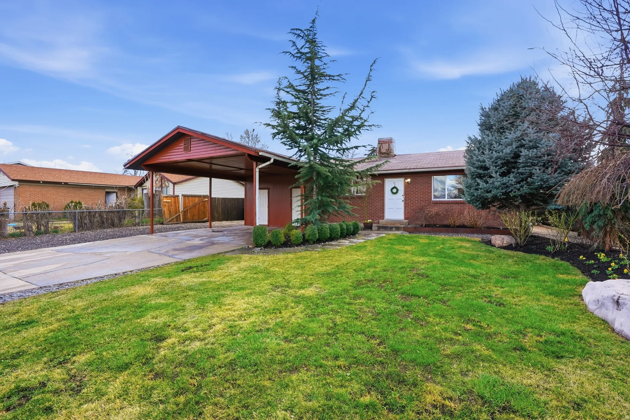 Ranch-style home with a chimney, concrete driveway, brick siding, and a carport