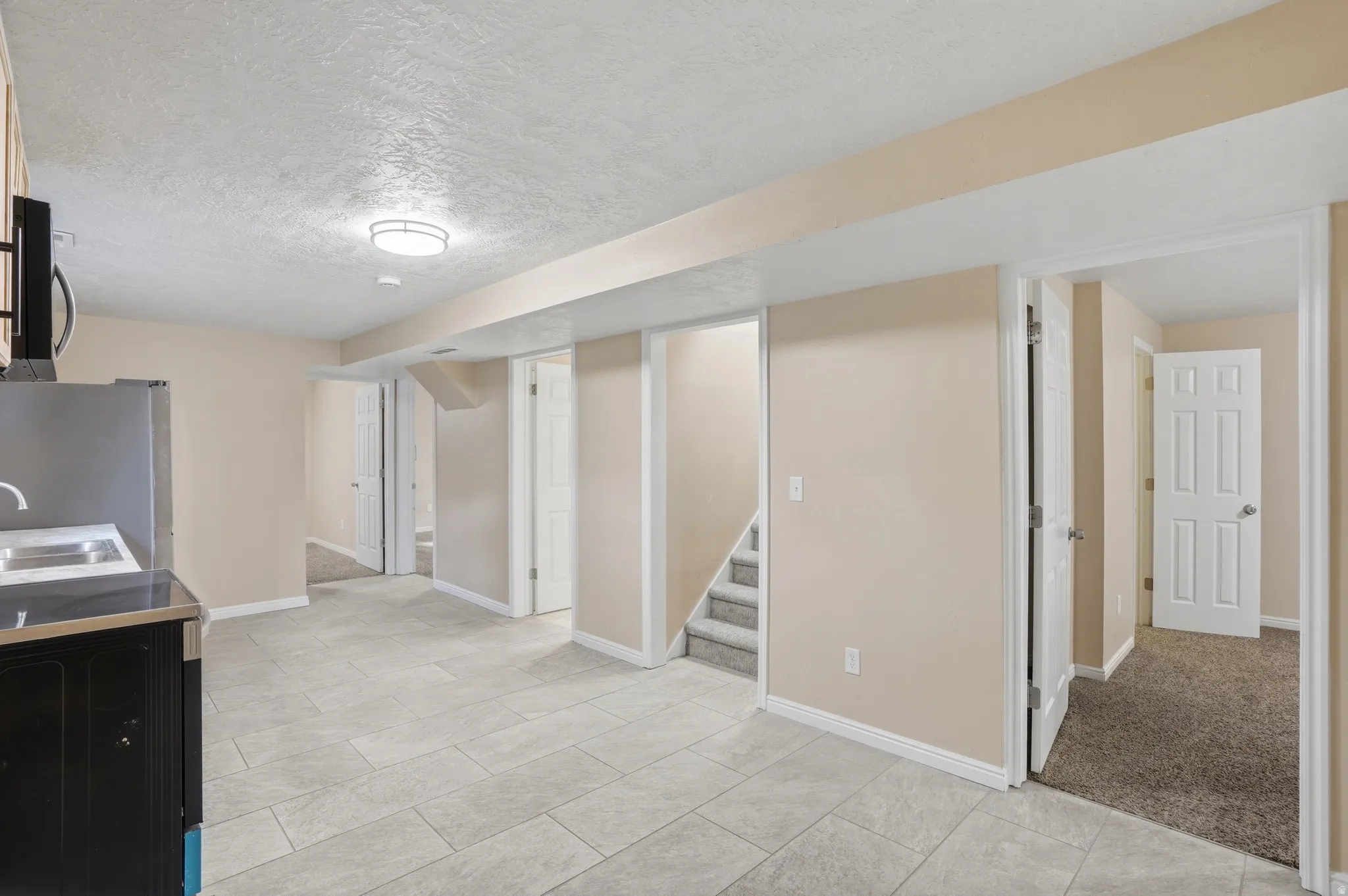 Kitchen with a textured ceiling, stainless steel appliances, and light tile patterned floors