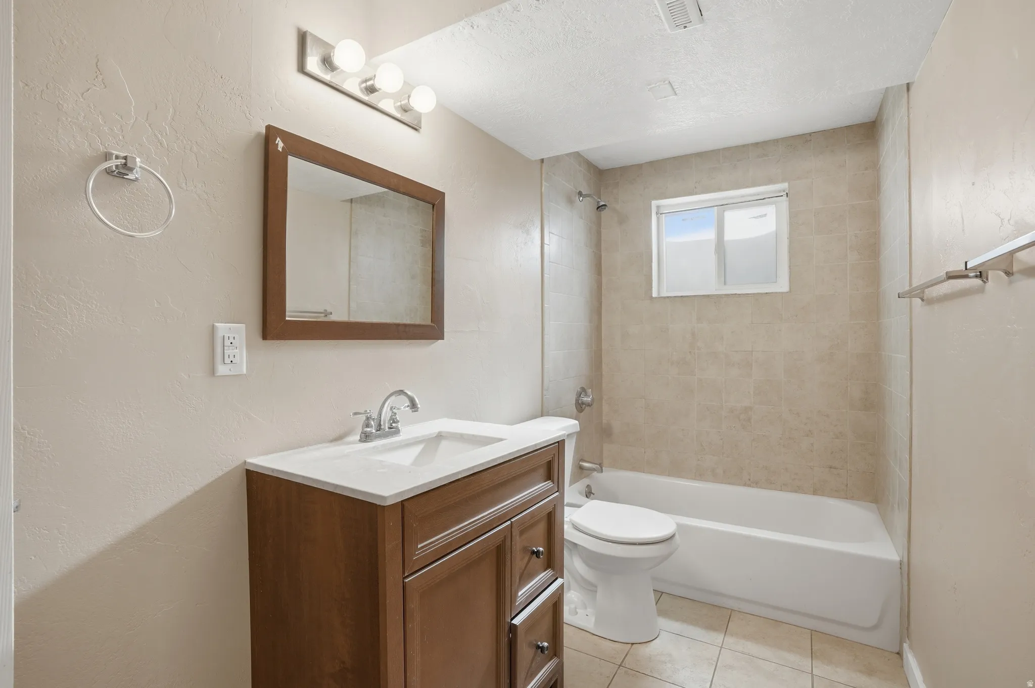 Bathroom featuring a textured wall, vanity, bathing tub / shower combination, light tile patterned floors, and a textured ceiling