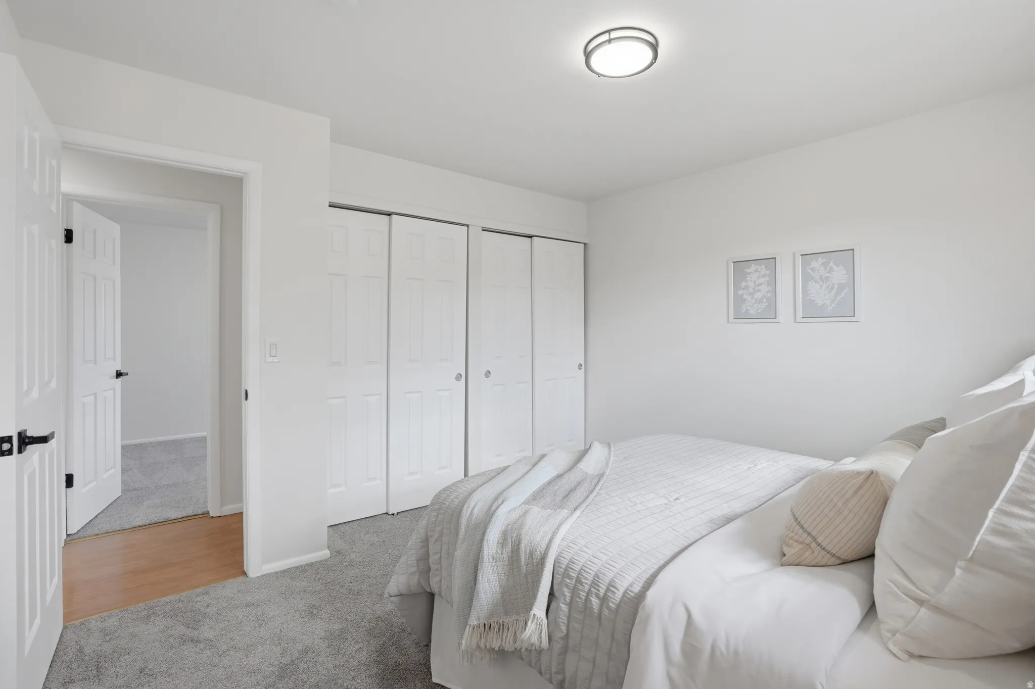 Bedroom with light colored carpet and two closets