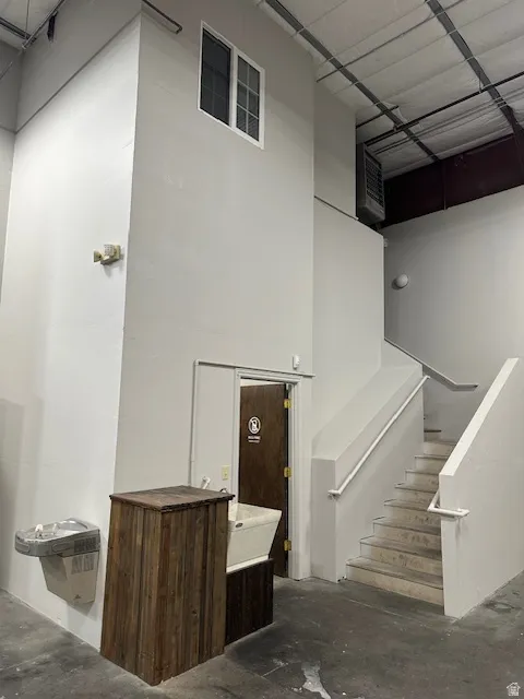 Staircase featuring unfinished concrete flooring, a heating unit, and a high ceiling