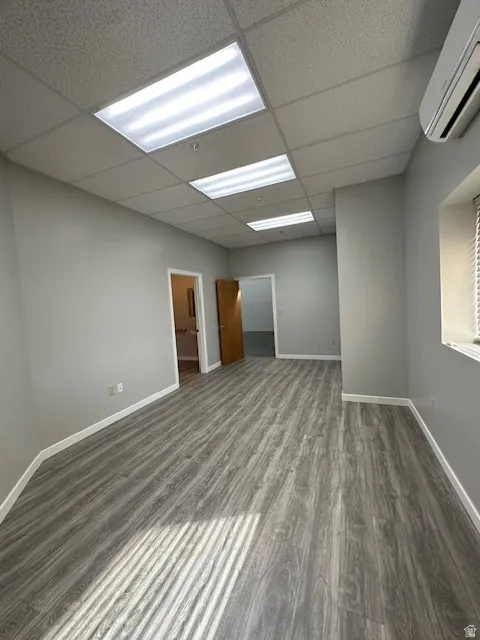 Unfurnished room featuring dark wood-style flooring and a paneled ceiling