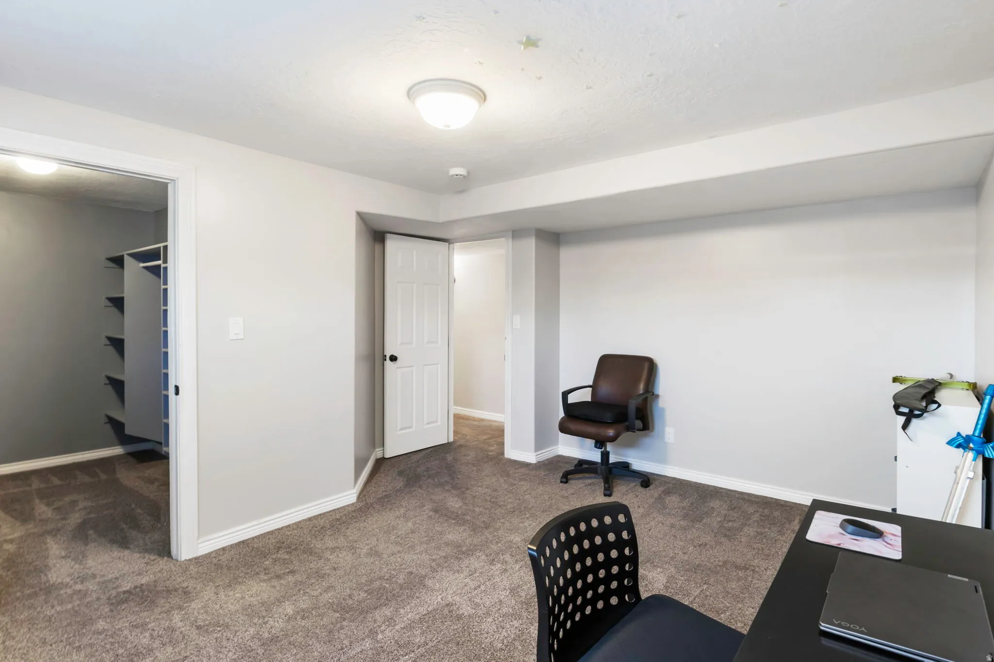 Home office with dark colored carpet and baseboards