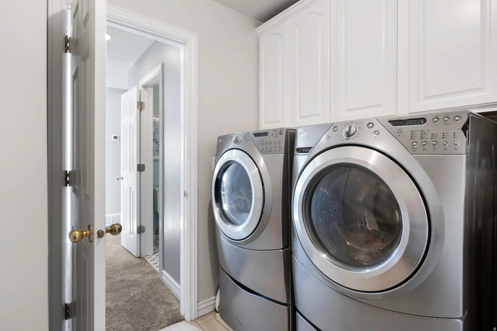 Laundry room featuring cabinet space, washer and clothes dryer, and light carpet
